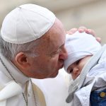 Papa Francesco bacia un bambino al suo arrivo a San Pietro durante il consueto giro in papamobile.