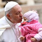 Bergoglio bacia un bambino all'udienza generale.