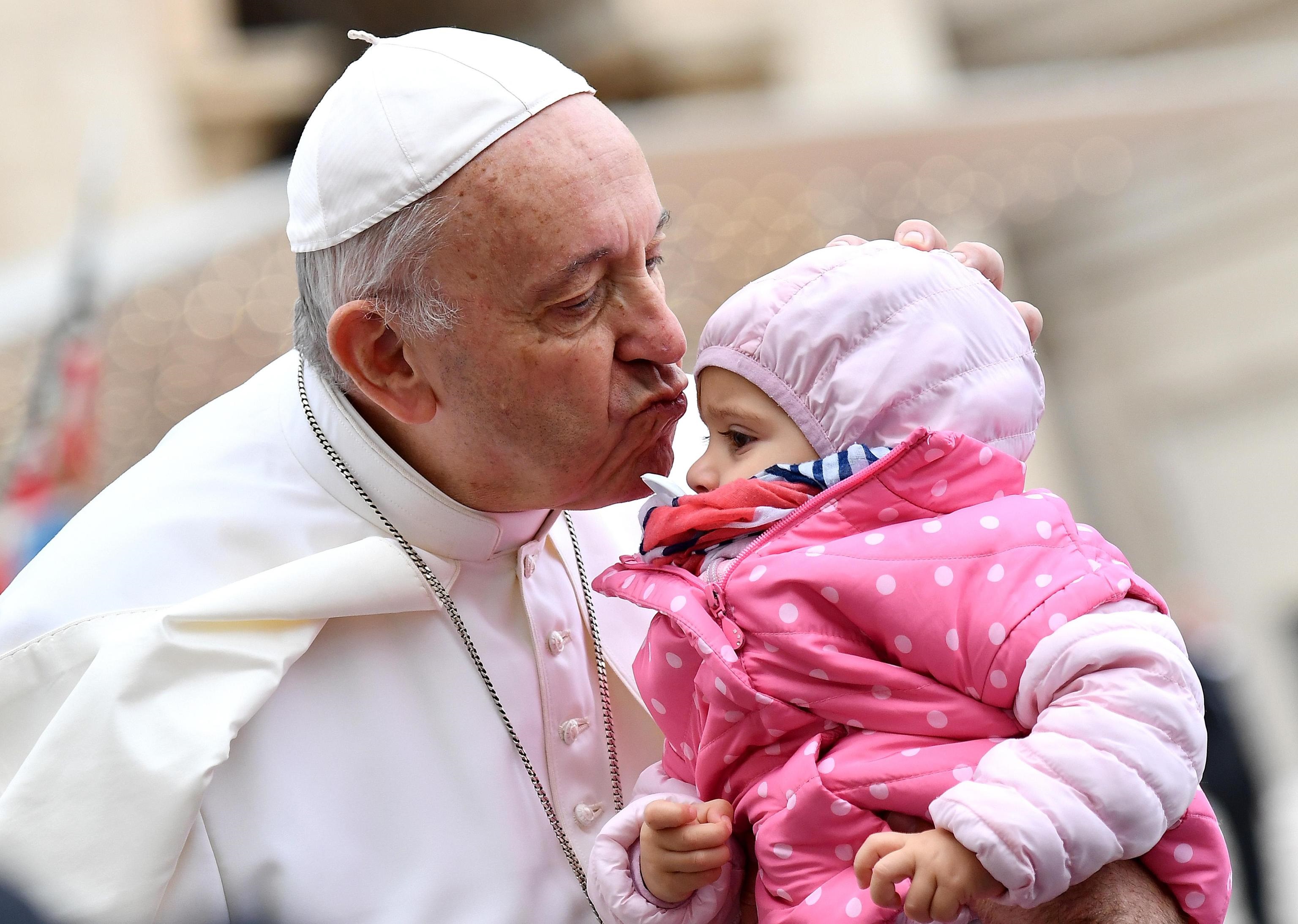Bergoglio bacia un bambino all'udienza generale.