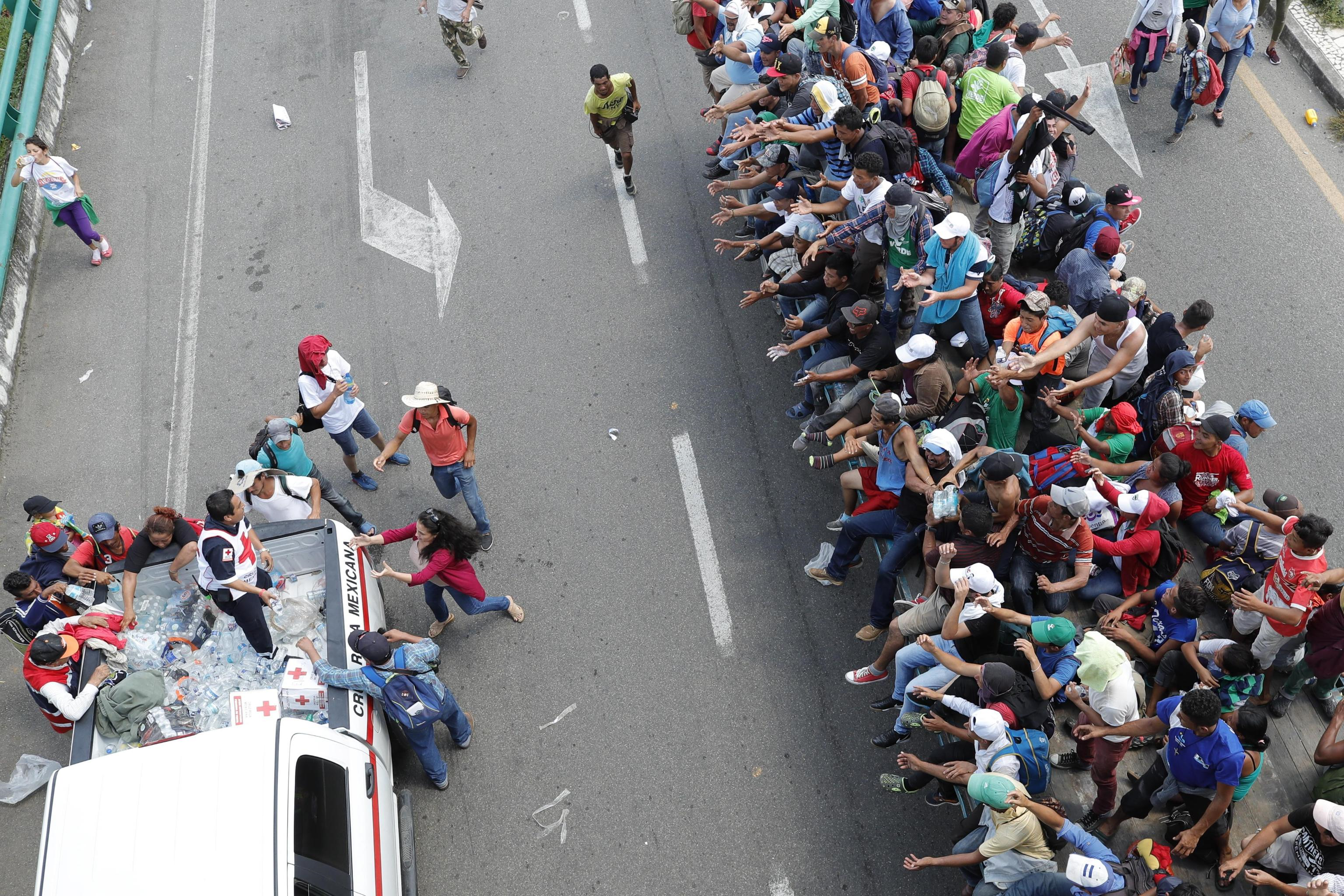 Membri della Croce Rossa consegnano l'acqua ai migranti honduregni