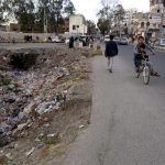 Passanti che camminano accanto alla spazzatura.