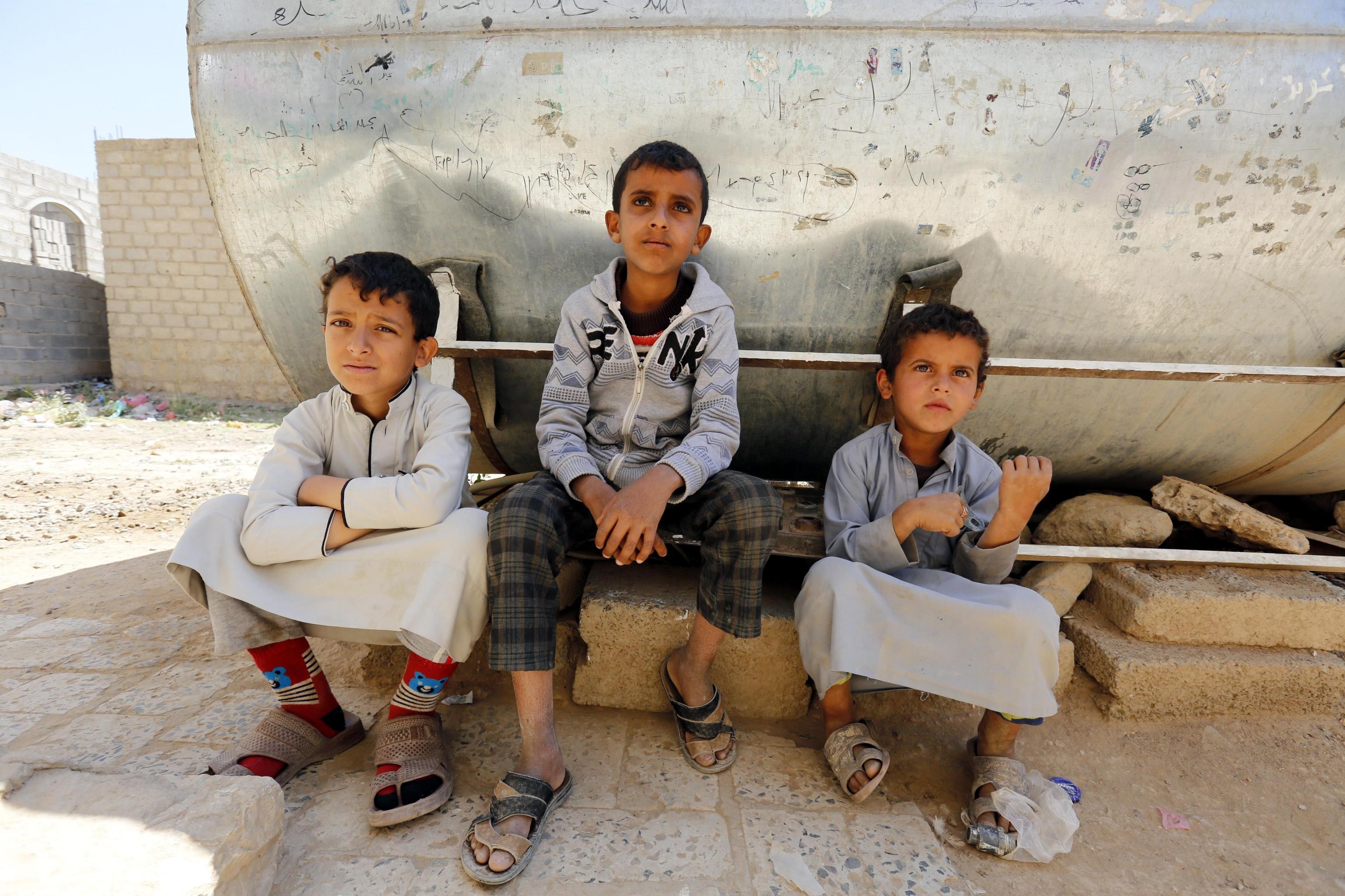 Bambini seduti accanto al serbatoio d'acqua contaminato.
