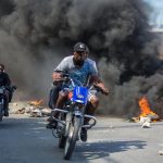 Alcuni motociclisti passano attraverso le barricate infuocate durante le proteste Alcuni motociclisti passano attraverso le barricate infuocate durante le proteste