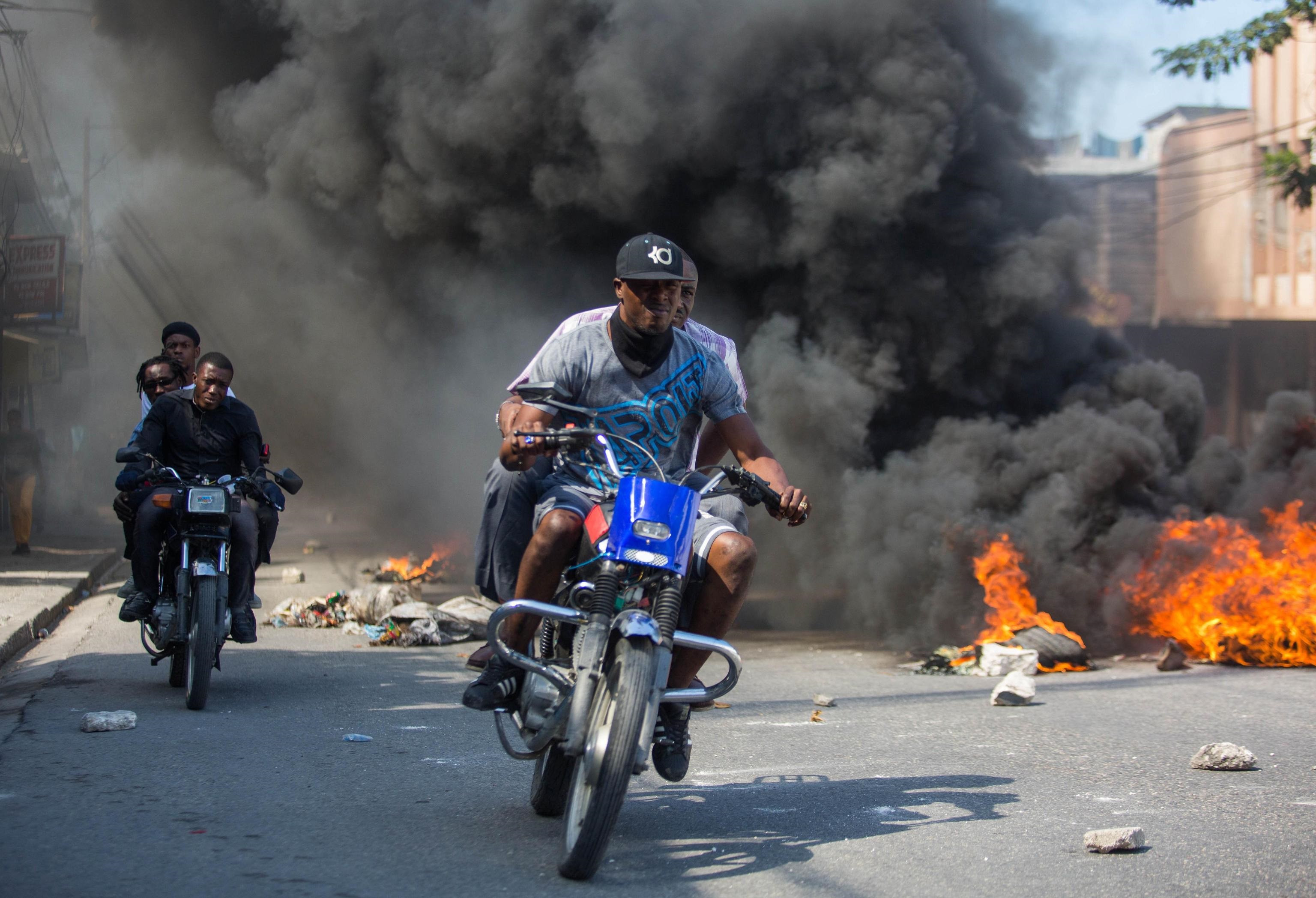 Alcuni motociclisti passano attraverso le barricate infuocate durante le proteste Alcuni motociclisti passano attraverso le barricate infuocate durante le proteste