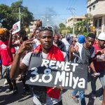 Un uomo con un cartello di protesta che cita i 3,8 miliardi di dollari ricevuti dal governo Un uomo con un cartello di protesta che cita i 3,8 miliardi di dollari ricevuti dal governo