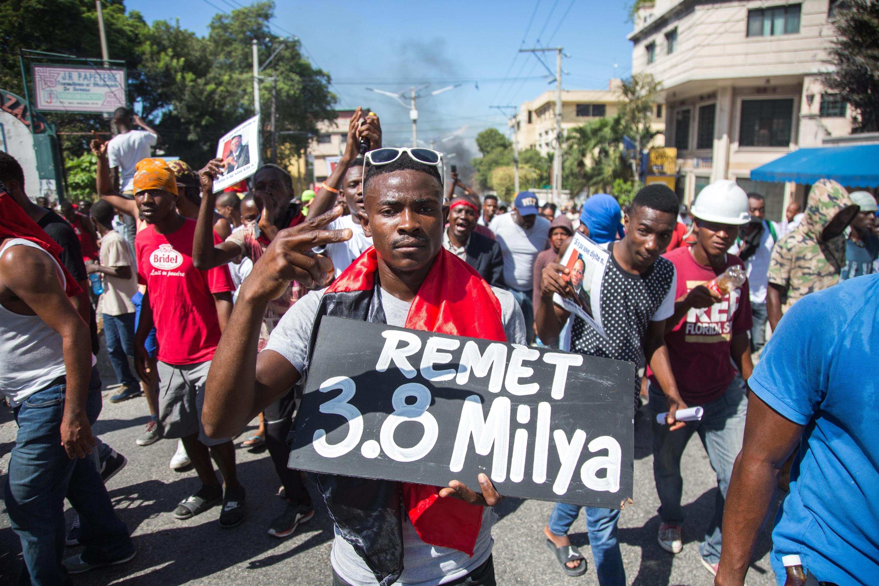Un uomo con un cartello di protesta che cita i 3,8 miliardi di dollari ricevuti dal governo Un uomo con un cartello di protesta che cita i 3,8 miliardi di dollari ricevuti dal governo