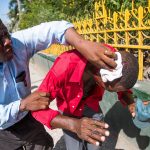 Un manifestate ferito alla testa viene aiutato da un uomo
