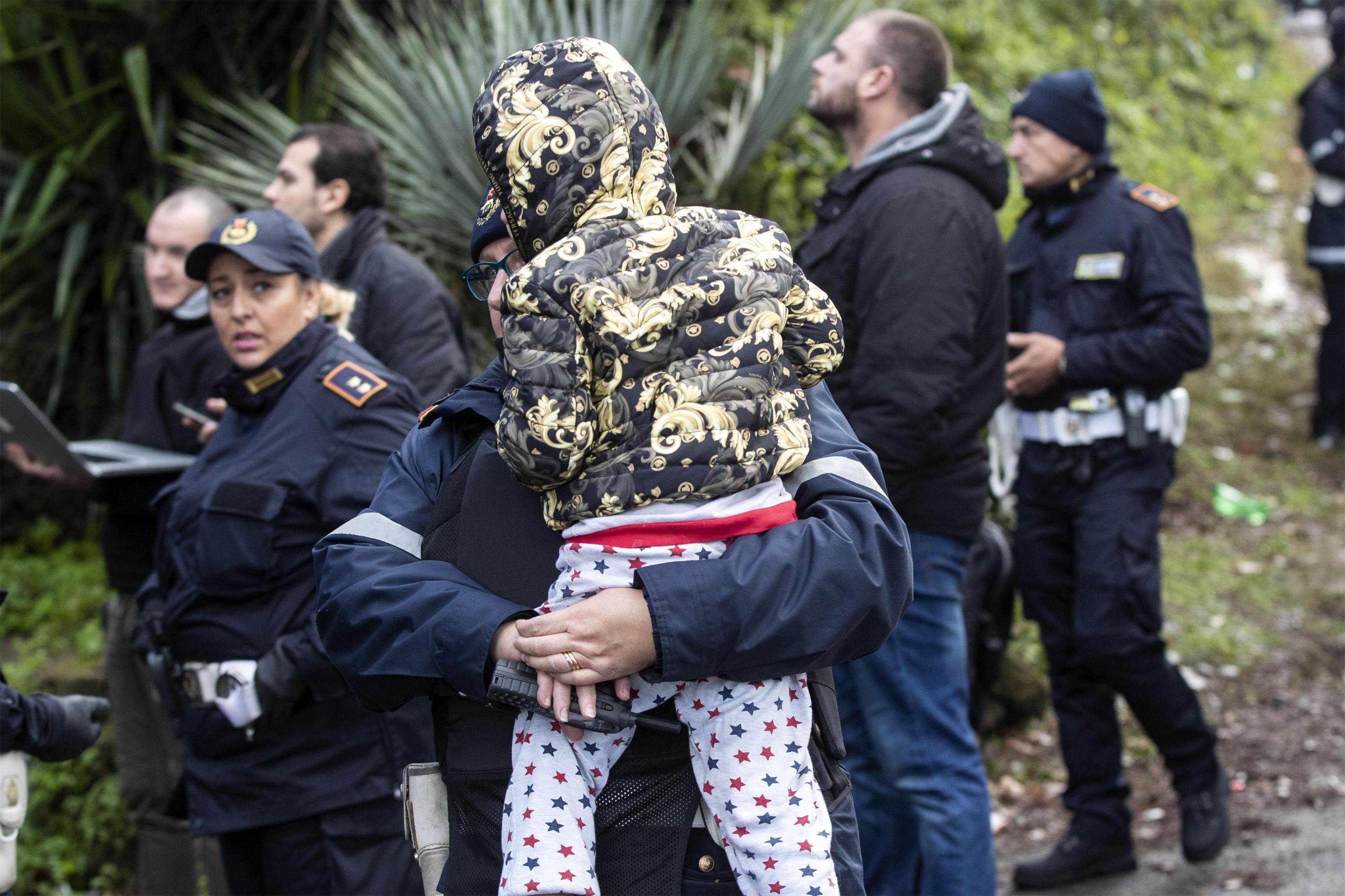 Una bambina viene portata via da un agente durante lo sgombero