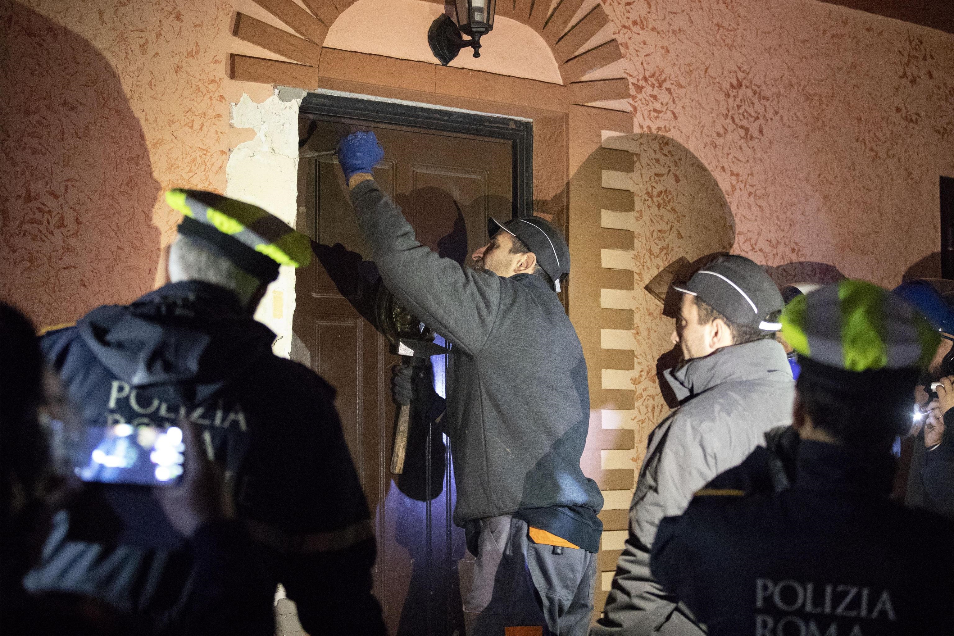 Un agente scardina una porta di ingresso