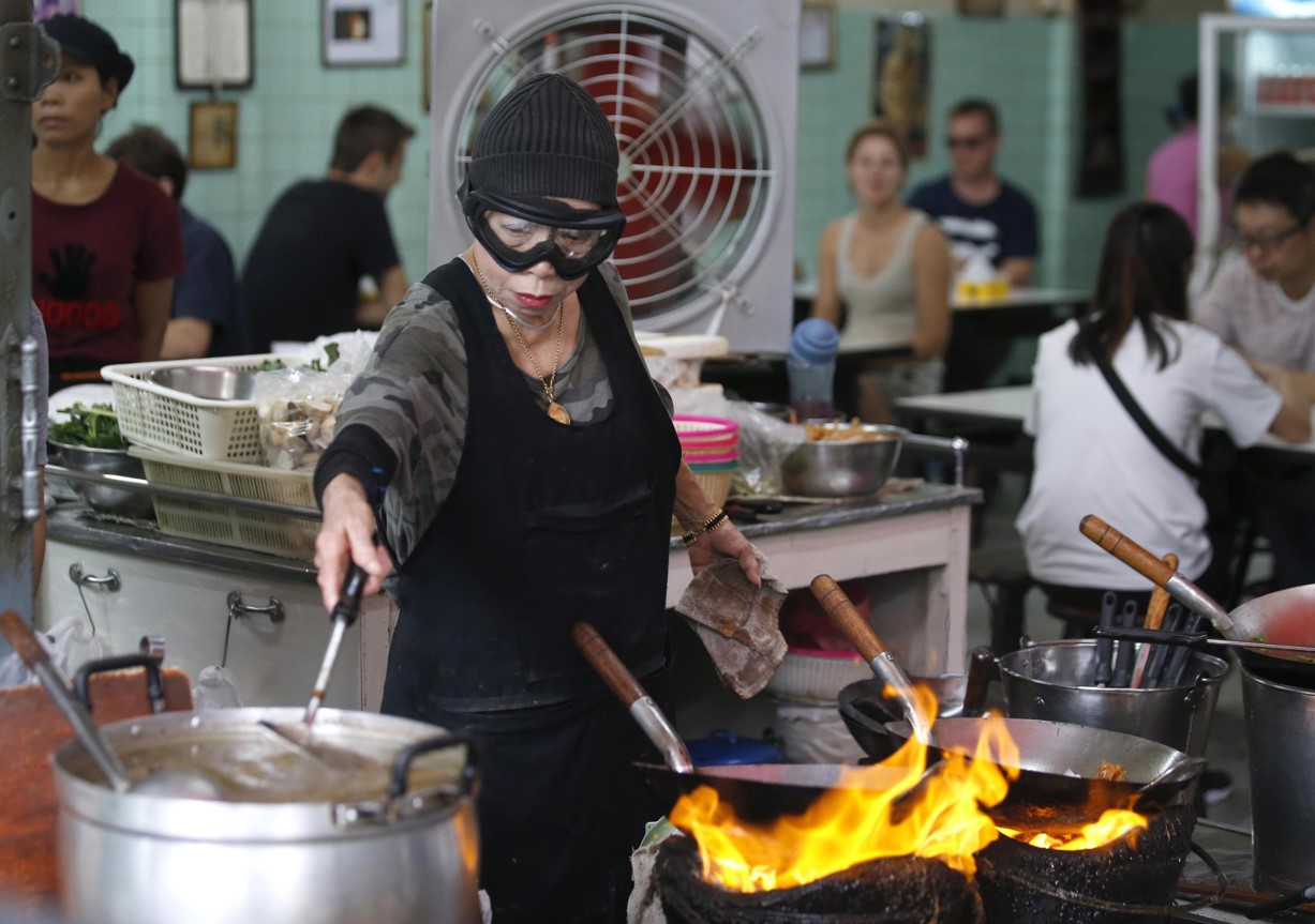La chef e proprietaria del Raan Jay Fai, Supinya Chansuta, mentre cucina con la sua mascherina