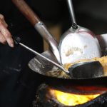 Omelette di granchio cotta dalla chef in padella su una stufa a carbone