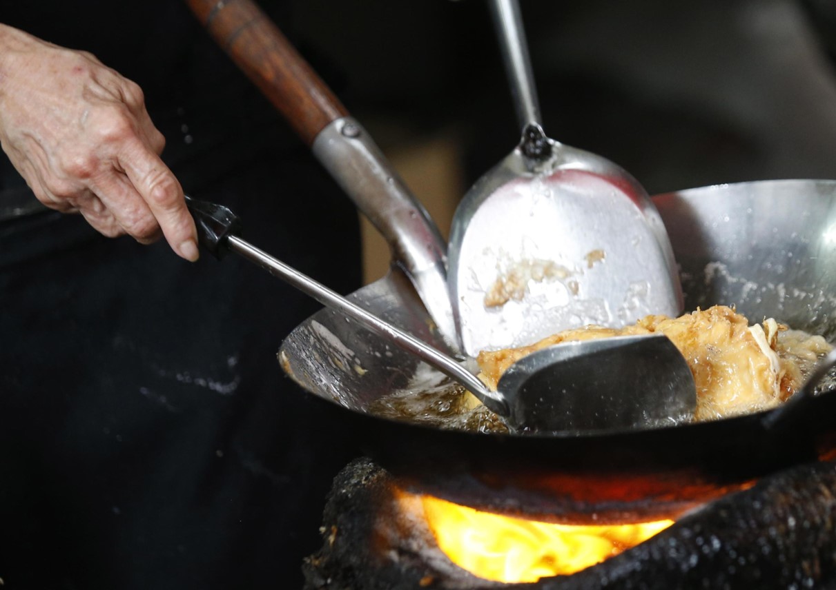 Omelette di granchio cotta dalla chef in padella su una stufa a carbone
