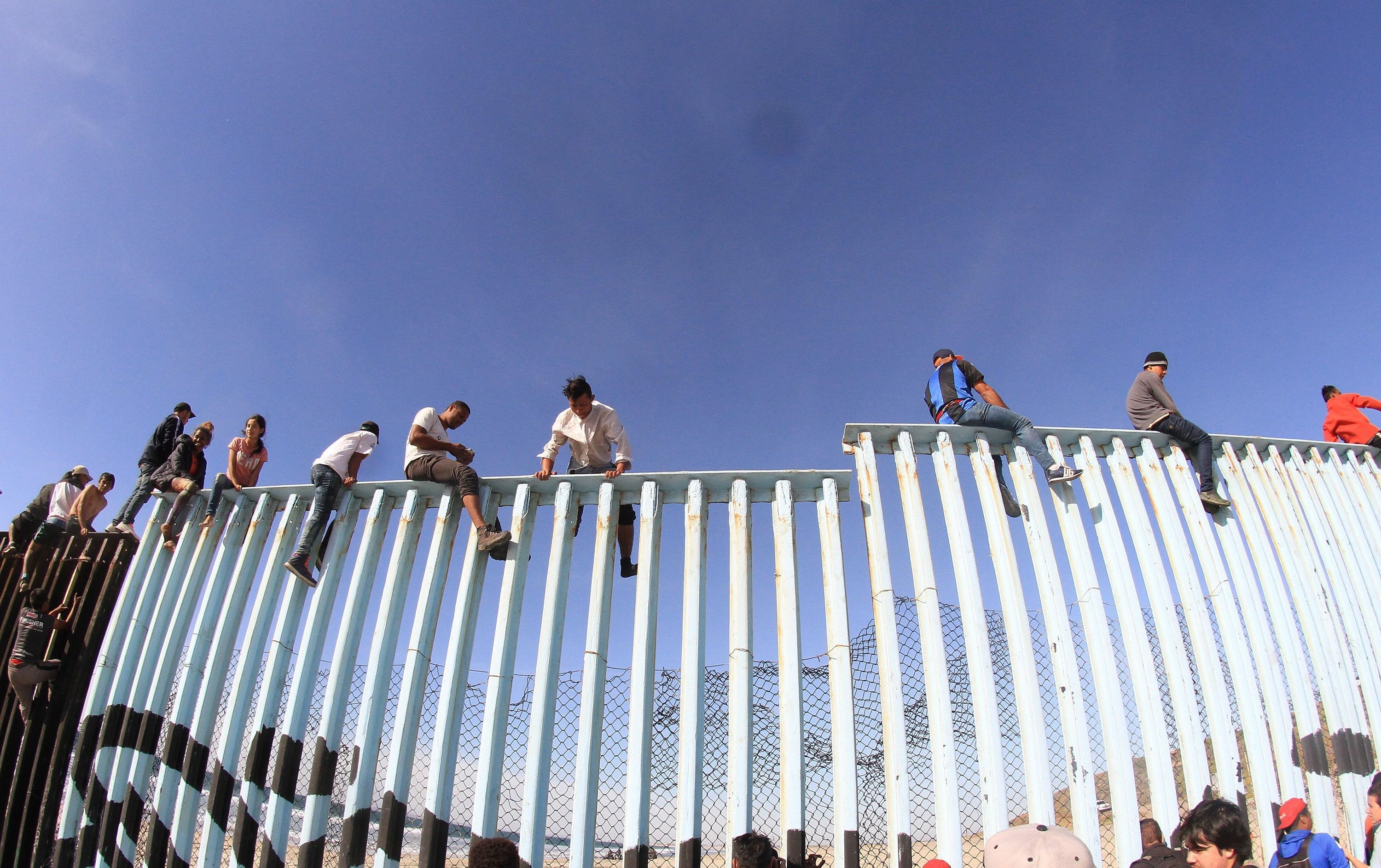 I migranti oltrepassano il recinto che divide i due Paesi