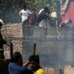 Gli abitanti delle capanne aiutano i vigili del fuoco locali a spegnere l'incendio che ha distrutto la baraccopoli