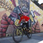 Remy Metailler (avanti), francese, e Sebastian Posada (dietro), spagnolo, percorrono una strada all'ombra di un murales Remy Metailler (avanti), francese, e Sebastian Posada (dietro), spagnolo, percorrono una strada all'ombra di un murales