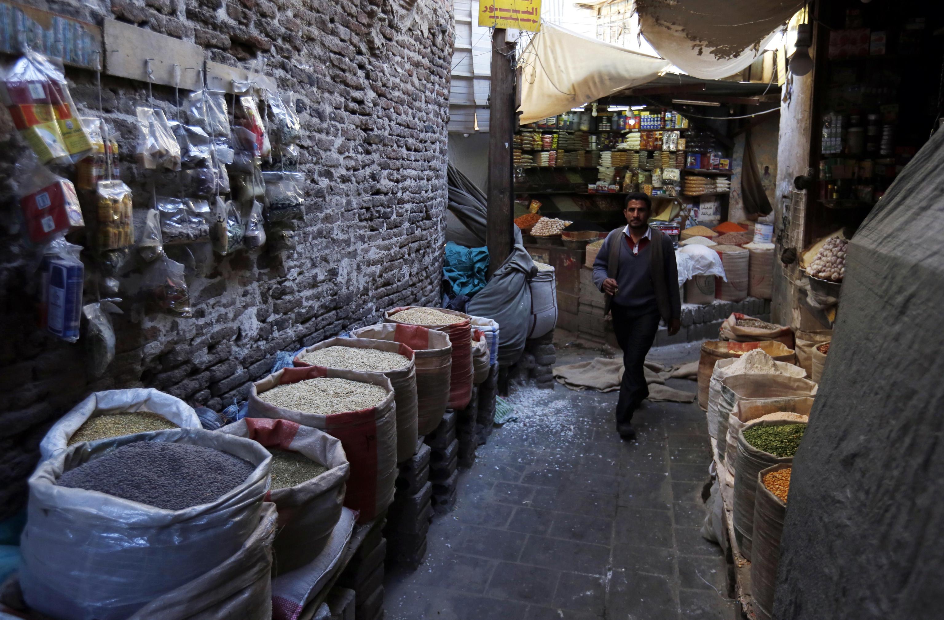 Uno yemenita passeggia lungo le vie anguste del mercato, ricco di prodotti e spezie.