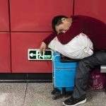 Un passeggero dorme nella stazione ferroviaria di Guangzhou nell'attesa del proprio treno verso casa in occasione del capodanno lunare