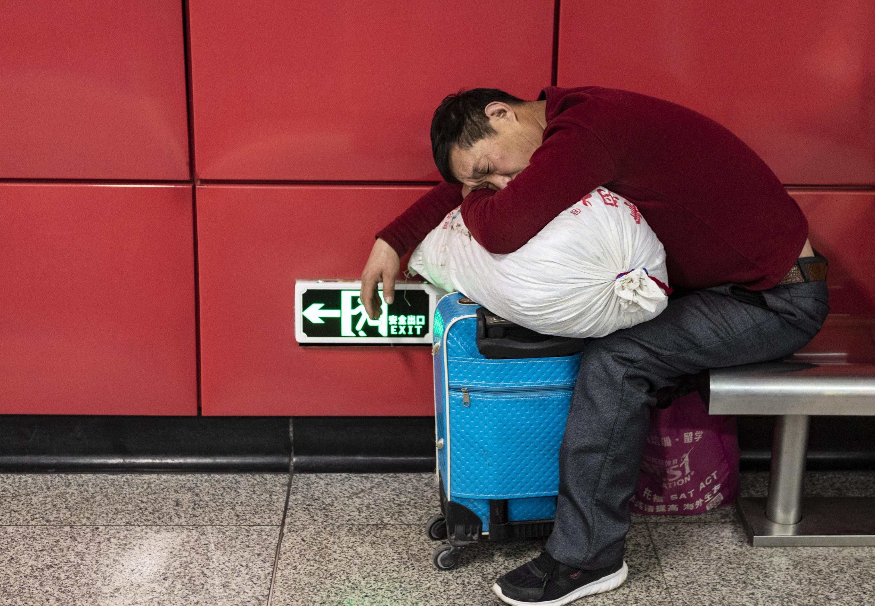 Un passeggero dorme nella stazione ferroviaria di Guangzhou nell'attesa del proprio treno verso casa in occasione del capodanno lunare
