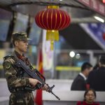 Un militare vigila sulla folla presente alla stazione ferroviaria di Guangzhou e in partenza per festeggiare con i propri cari il capodanno lunare