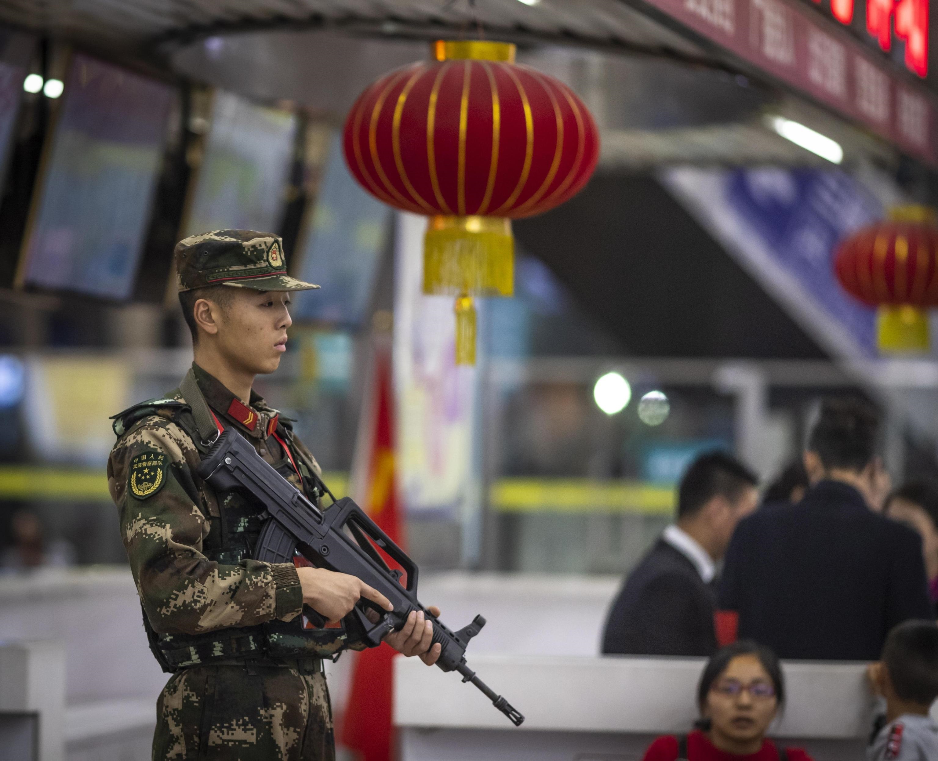 Un militare vigila sulla folla presente alla stazione ferroviaria di Guangzhou e in partenza per festeggiare con i propri cari il capodanno lunare
