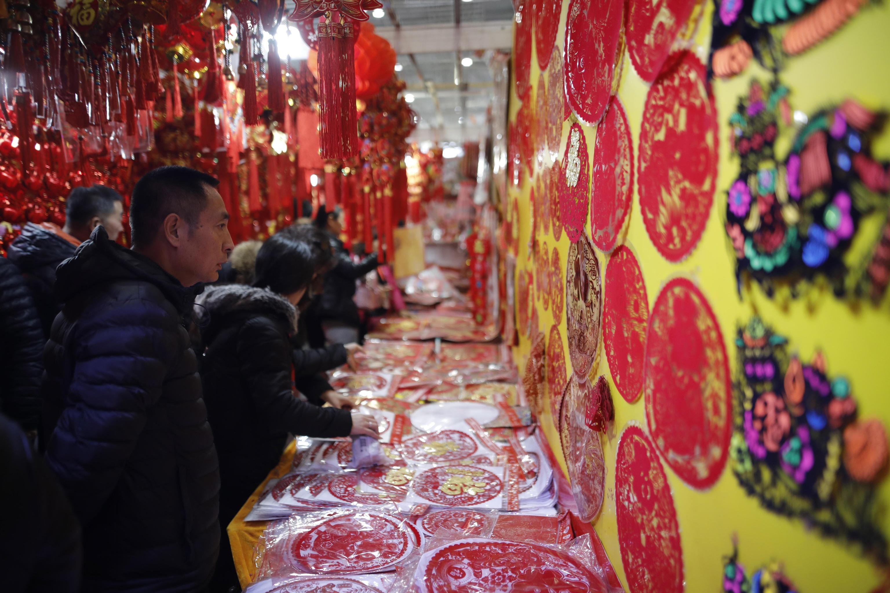 Un cliente guarda le decorazioni di capodanno al mercato di Pechino