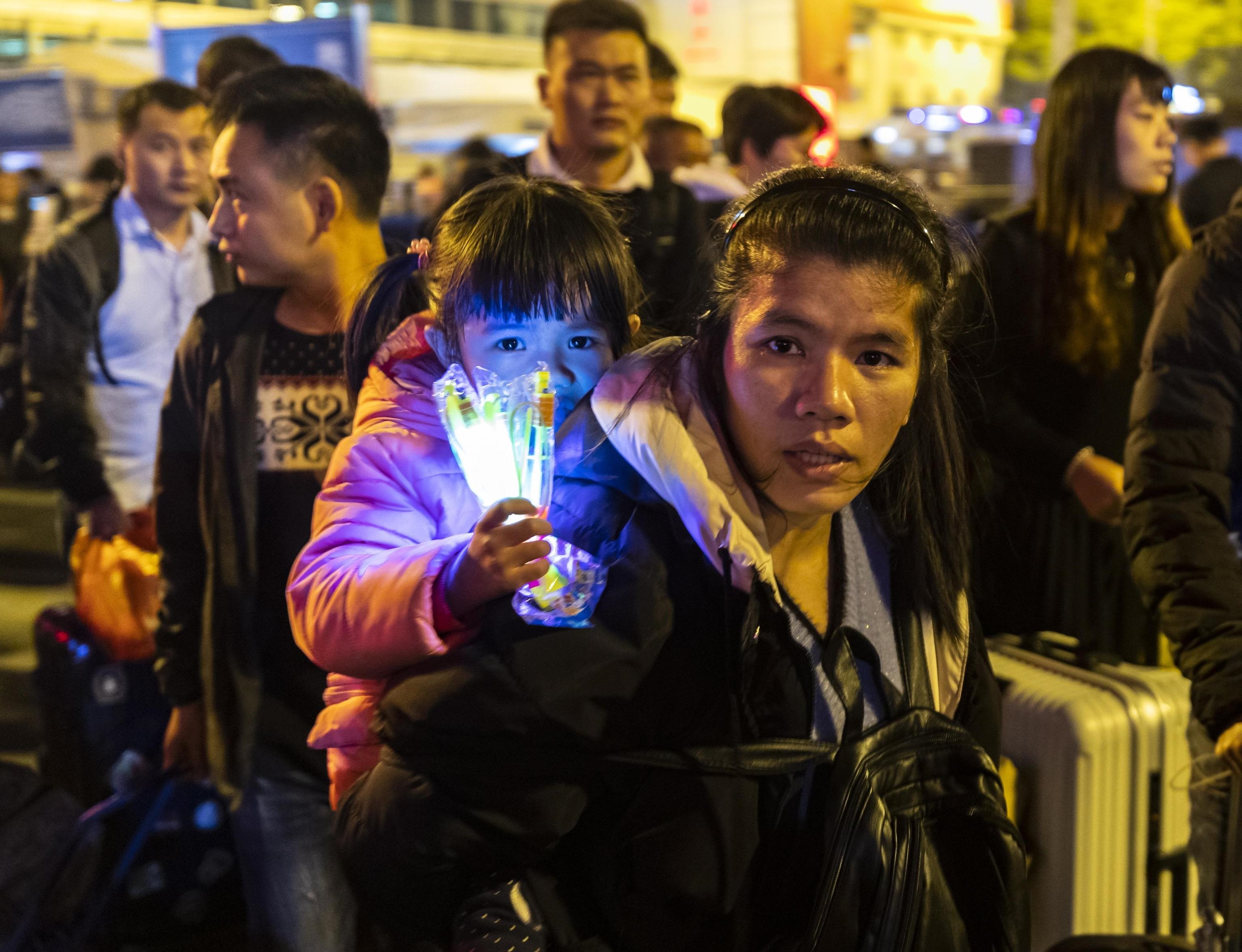 Giovane madre con bambina nella calca della stazione ferroviaria di Guangzhou, destinazione casa e festeggiamento del capodanno lunare cinese