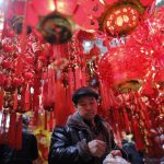 Un cliente del mercato di Pechino alle prese con l'acquisto delle decorazioni dedicate al festeggiamento del nuovo anno lunare cinese, scatterà il 5 febbraio l'anno del maiale