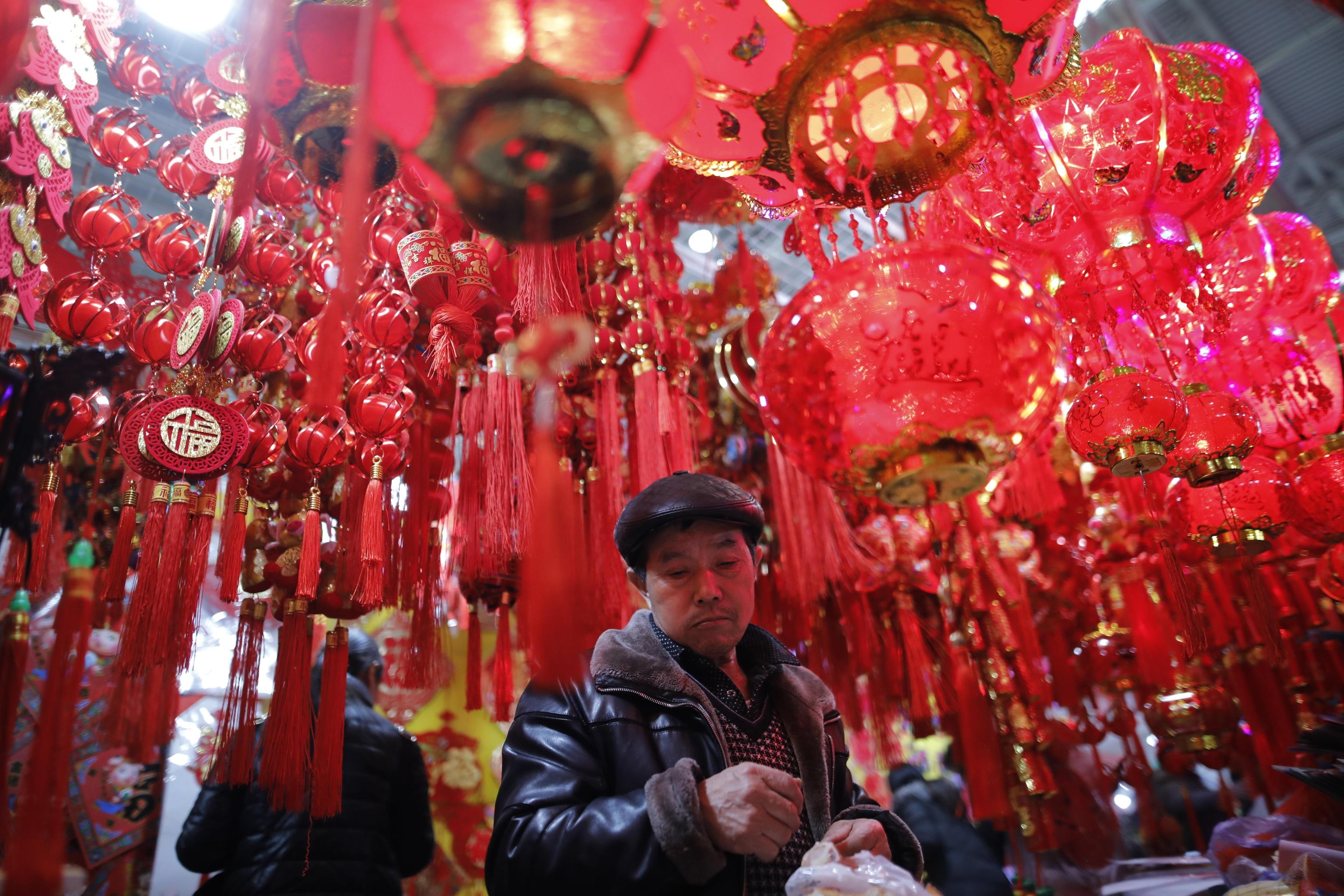 Un cliente del mercato di Pechino alle prese con l'acquisto delle decorazioni dedicate al festeggiamento del nuovo anno lunare cinese, scatterà il 5 febbraio l'anno del maiale