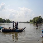 Un uomo e un bambino trascinano due gommoni con dei migranti honduregni sul fiume Suchiate (Ciudad Hidalgo, Messico) Un uomo e un bambino trascinano due gommoni con dei migranti honduregni sul fiume Suchiate (Ciudad Hidalgo, Messico)