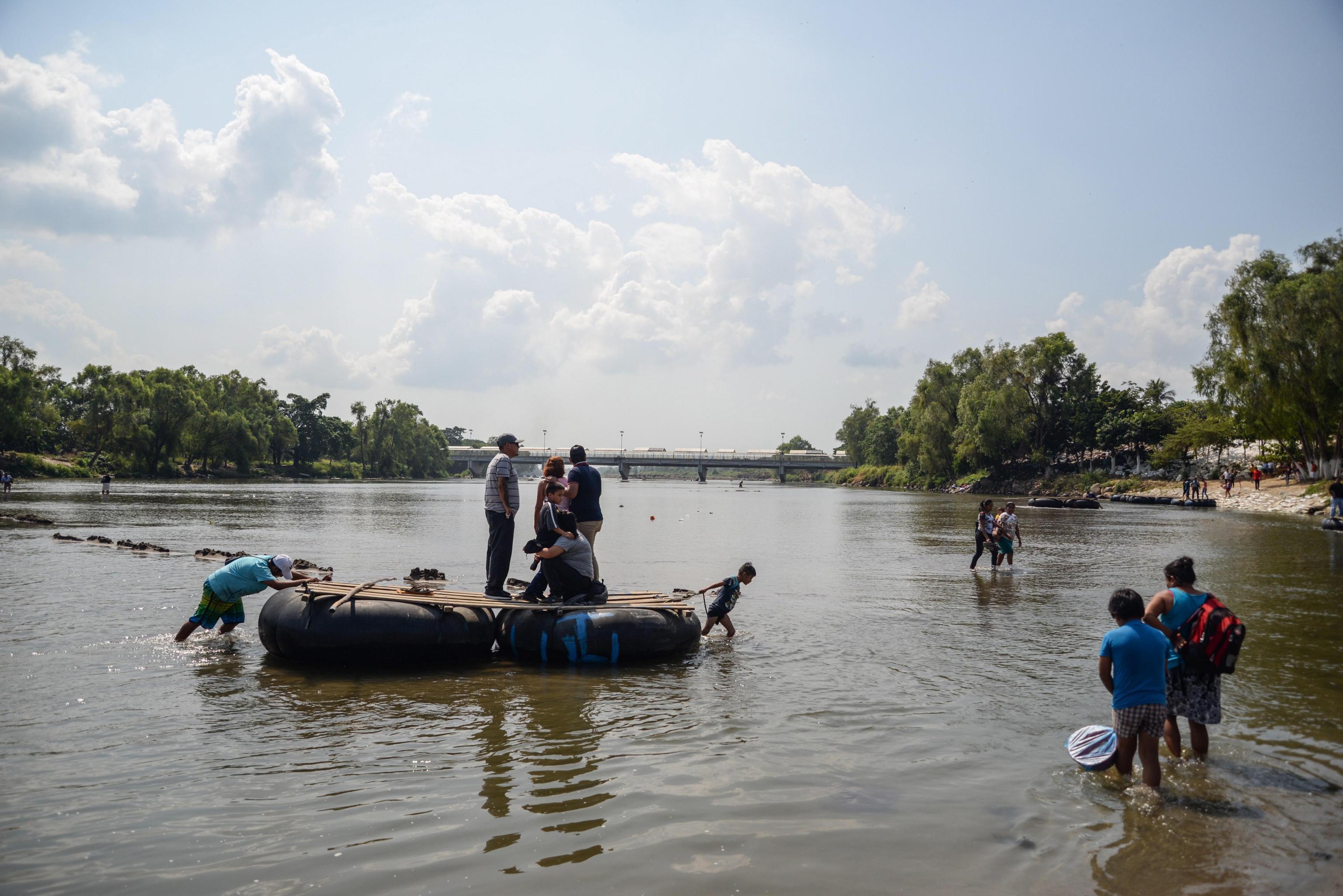 Un uomo e un bambino trascinano due gommoni con dei migranti honduregni sul fiume Suchiate (Ciudad Hidalgo, Messico) Un uomo e un bambino trascinano due gommoni con dei migranti honduregni sul fiume Suchiate (Ciudad Hidalgo, Messico)