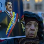 Una donna a Berlino tiene il ritratto di Nicolas Maduro