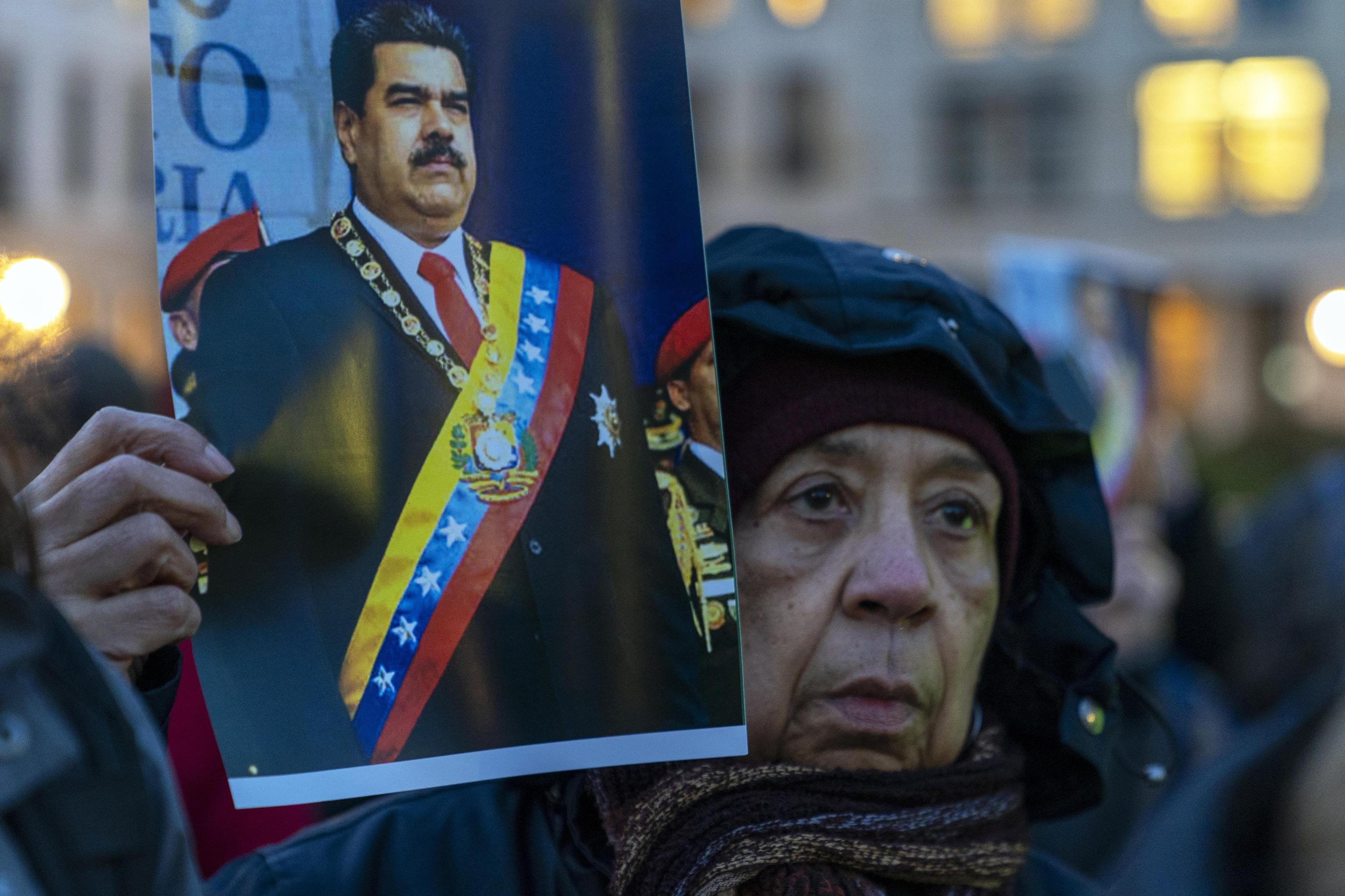 Una donna a Berlino tiene il ritratto di Nicolas Maduro