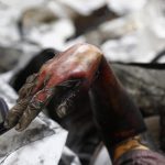 La mano di una vittima dell'incendio che esce fuori dalle macerie