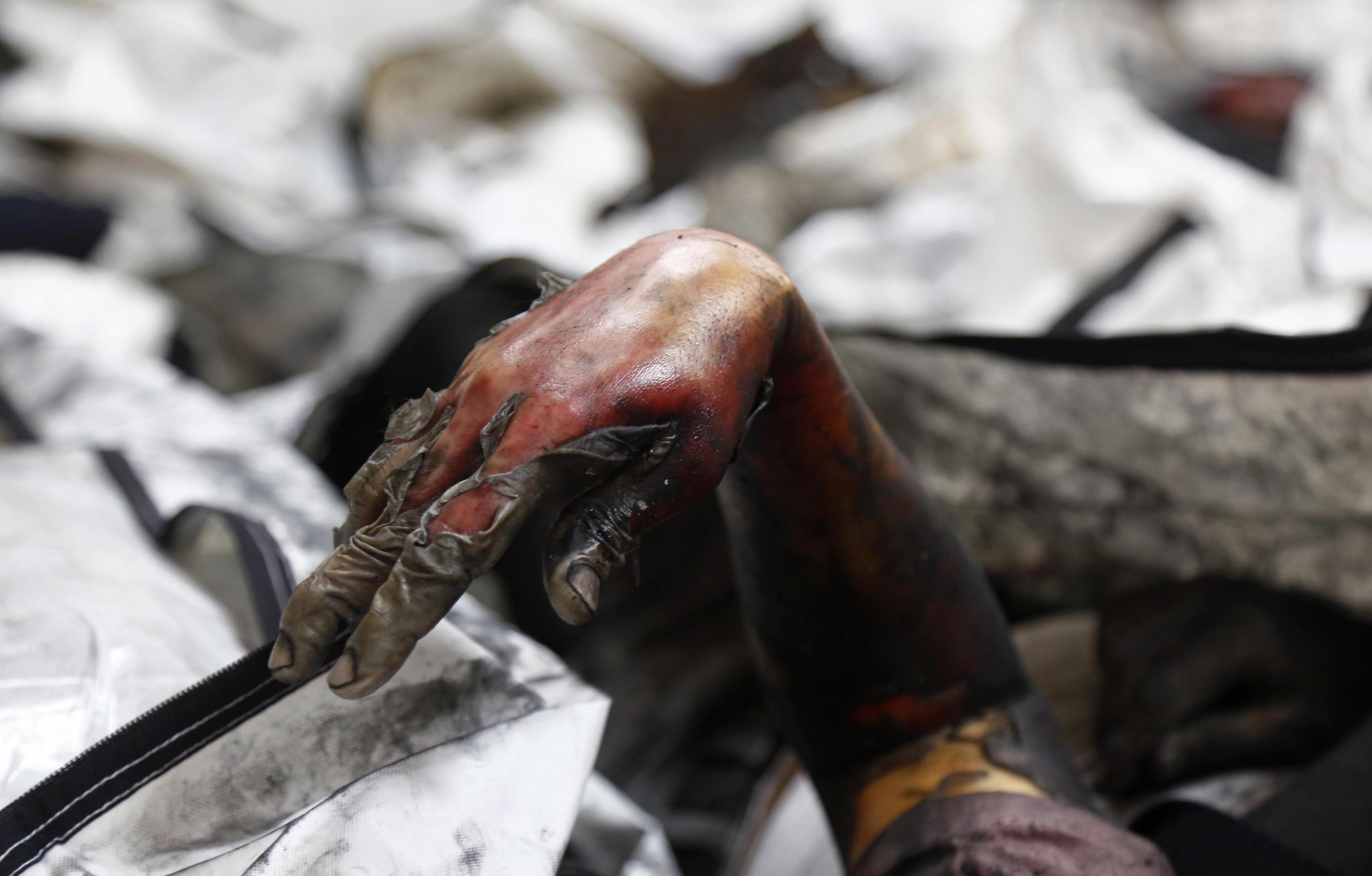 La mano di una vittima dell'incendio che esce fuori dalle macerie