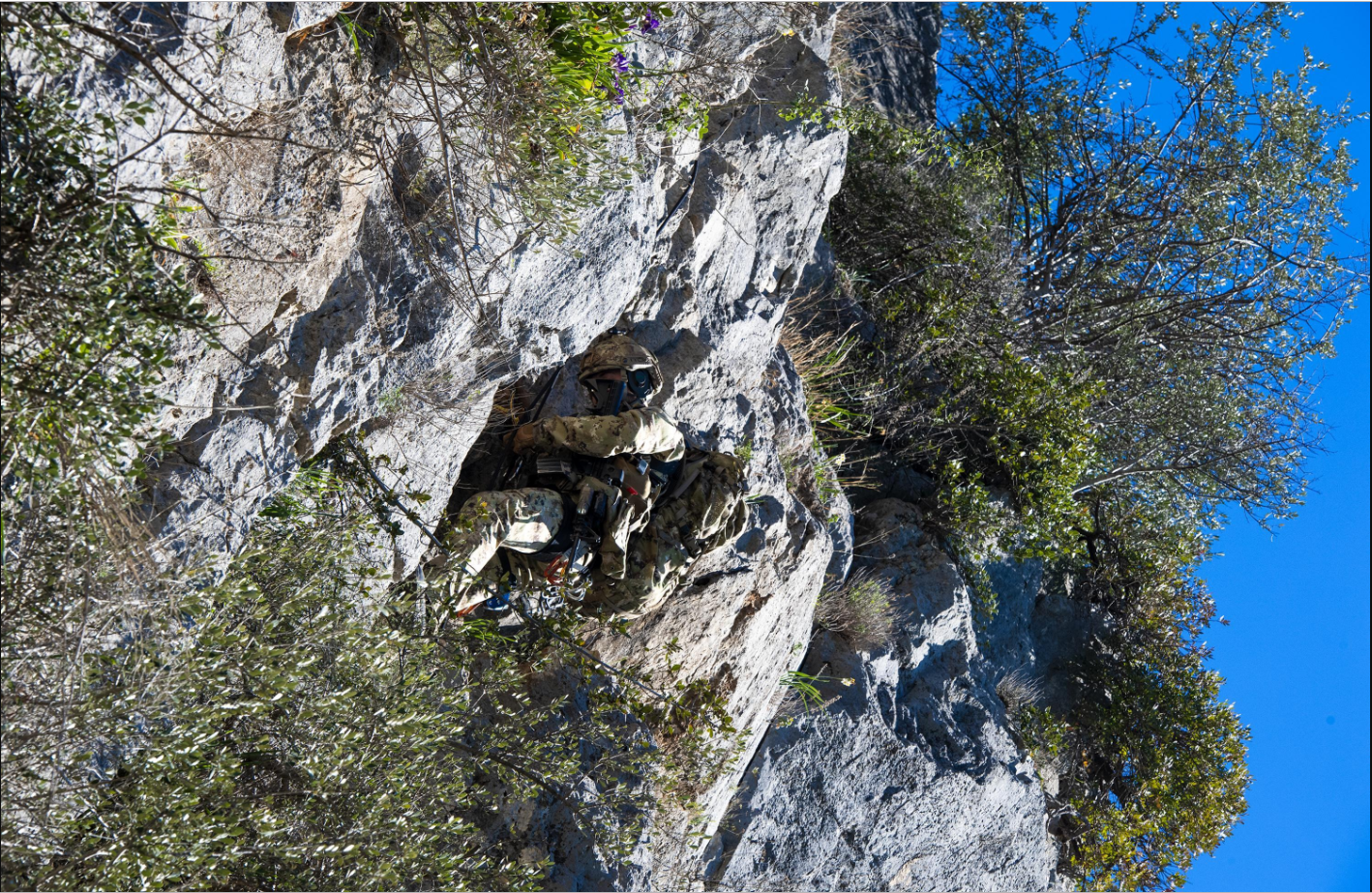 Un militare aggrappato alla roccia tramite una fune