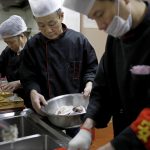 Alcuni chef alle prese con la preparazione del pesce in un ristorante di Beijing