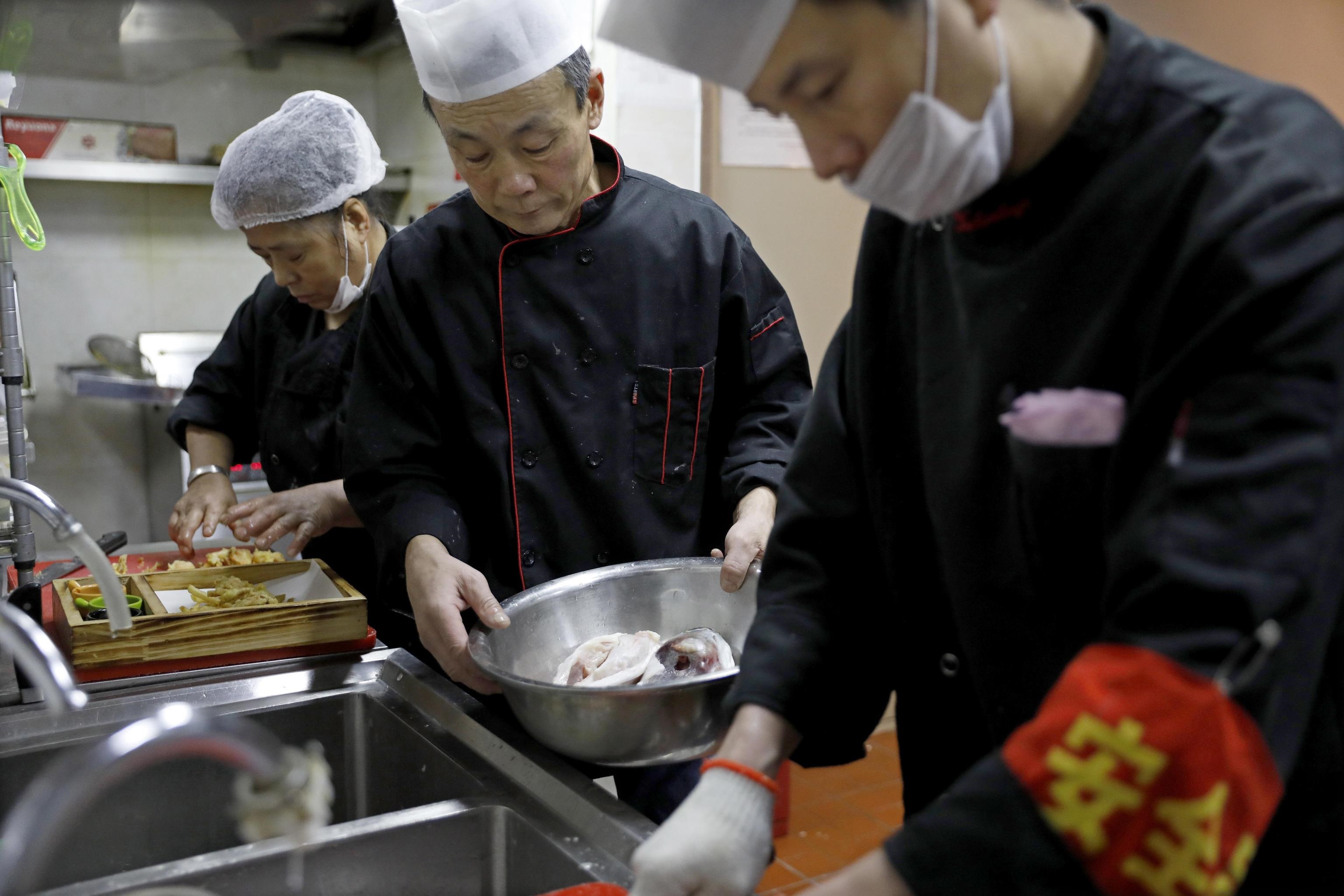 Alcuni chef alle prese con la preparazione del pesce in un ristorante di Beijing