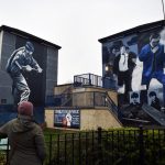 Una donna guarda i murales dipinti su di un edificio nel quartiere The Bogside a Londonderry nell’Irlanda del Nord.