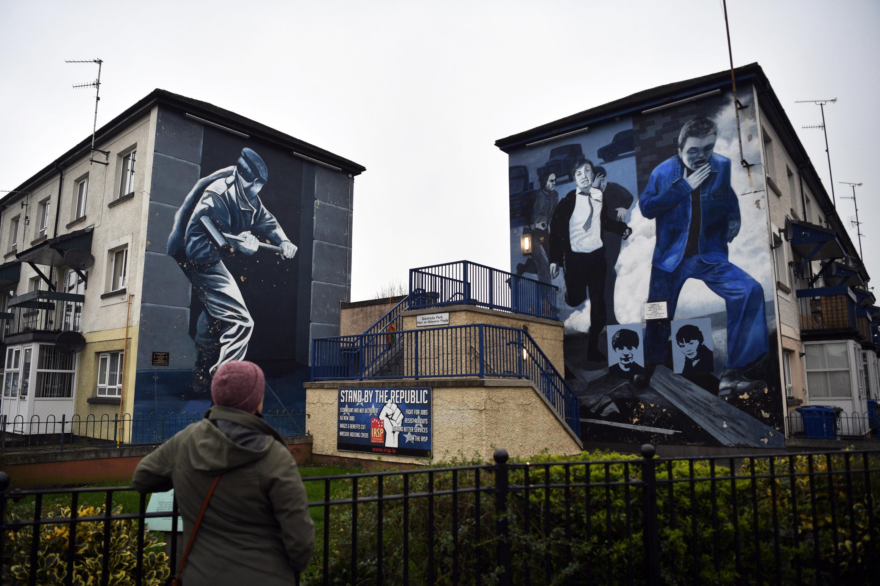 Una donna guarda i murales dipinti su di un edificio nel quartiere The Bogside a Londonderry nell’Irlanda del Nord.
