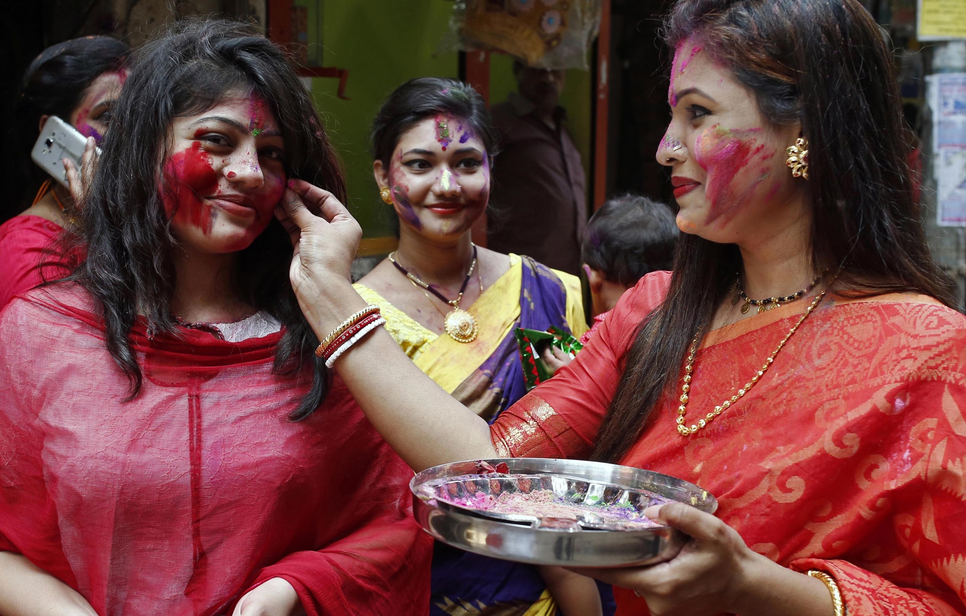 Una donna colora il viso di un'altra a Dacca