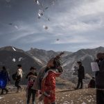 Una ragazza tibetana getta in aria un foglio con preghiere e speranze vicino al monastero di Labrang