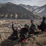 Un gruppo di tibetani seduti sulla stessa collina che domina il monastero di Labrang