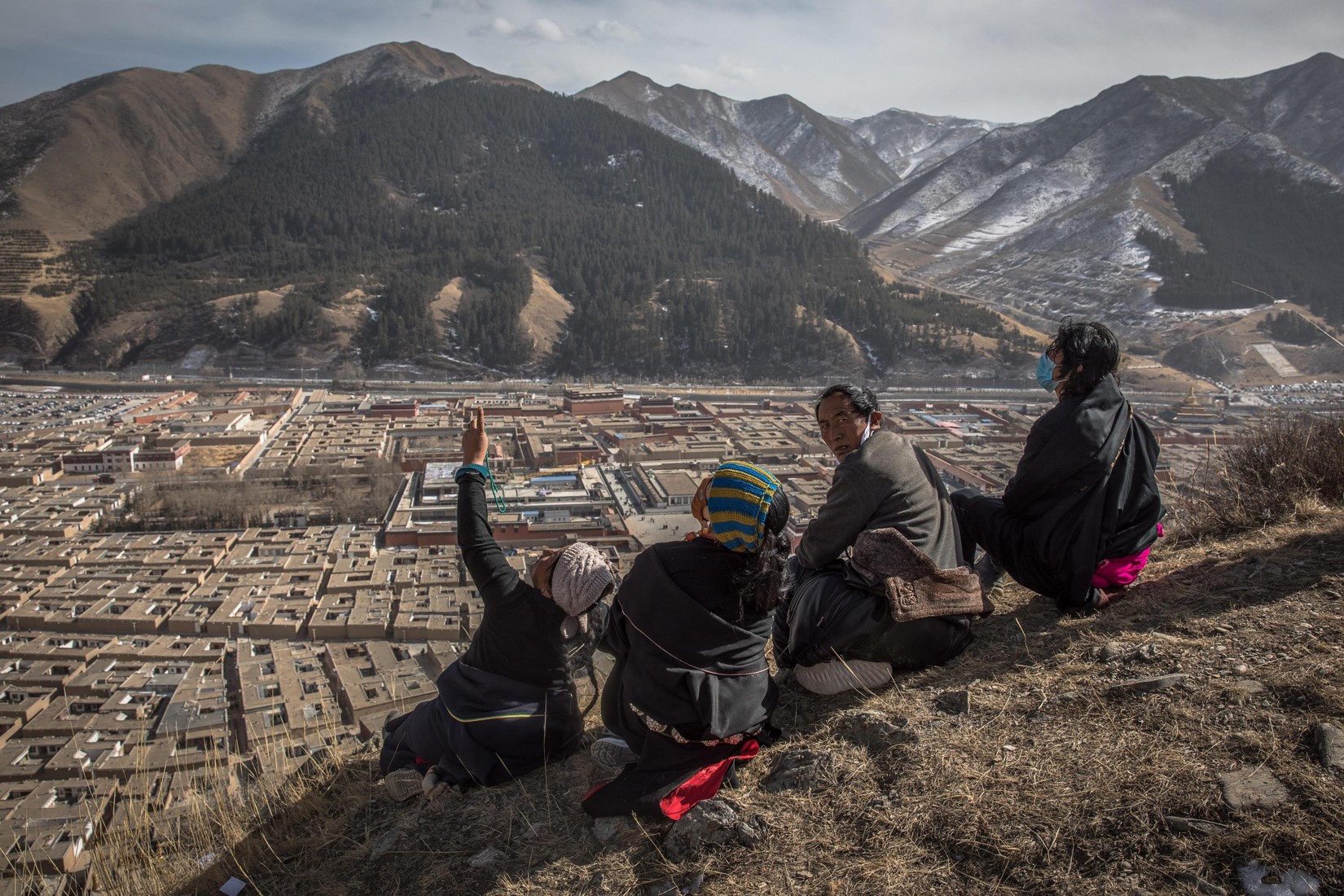 Un gruppo di tibetani seduti sulla stessa collina che domina il monastero di Labrang
