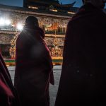 Alcuni monaci buddisti tibetani assistono alla cerimonia con le sculture fatte di burro di yak