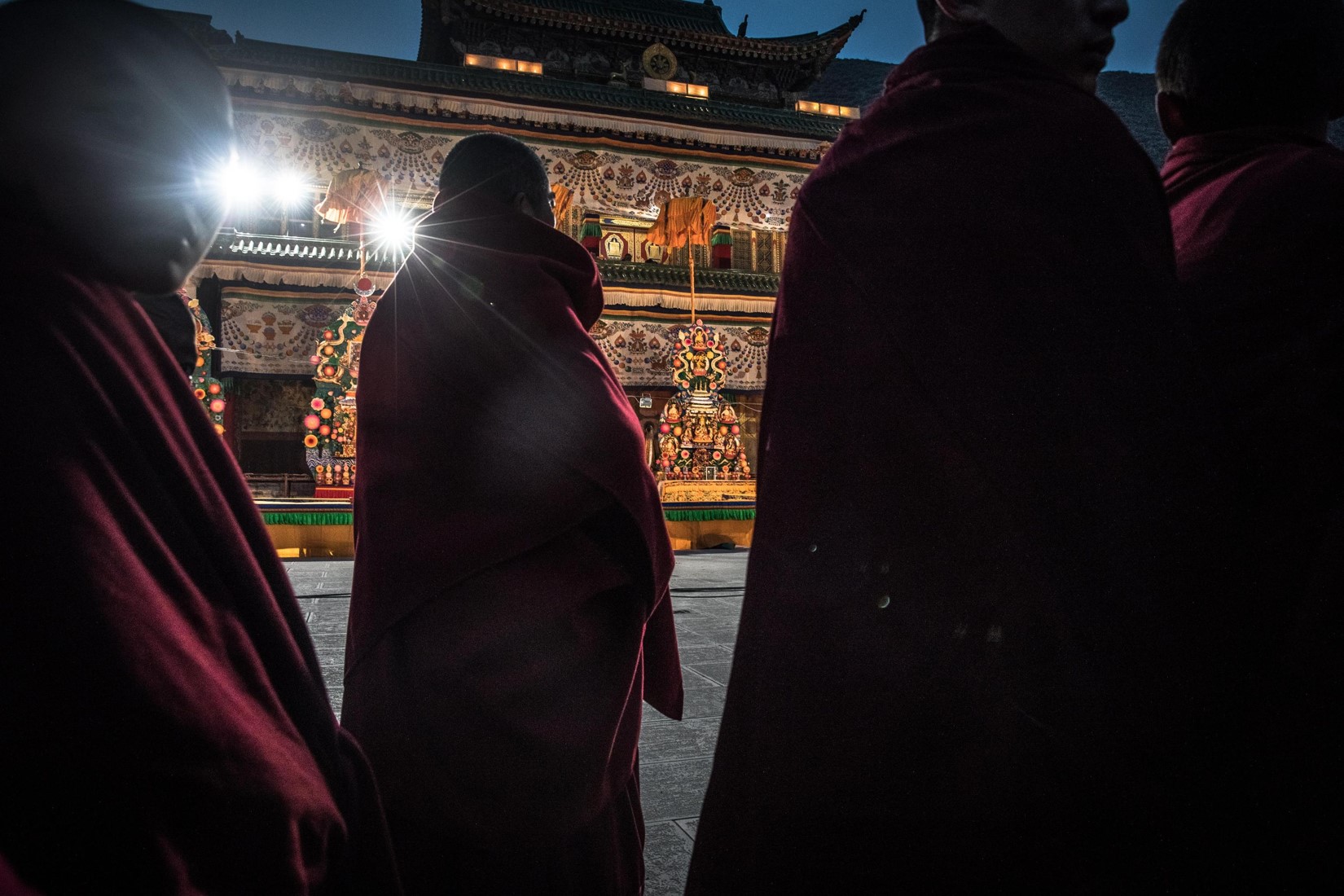 Alcuni monaci buddisti tibetani assistono alla cerimonia con le sculture fatte di burro di yak