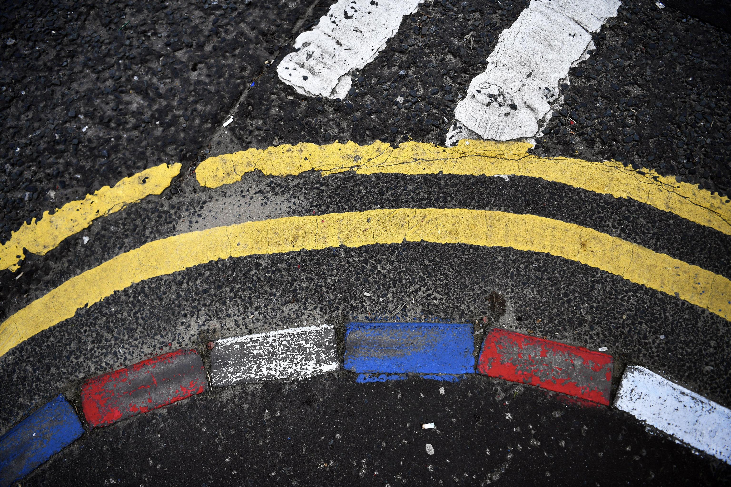 Le pietre di un marciapiede dipinte con i colori degli unionisti, accanto a due strisce di colori diversi che simboleggiano il confine Le pietre di un marciapiede dipinte con i colori degli unionisti, accanto a due strisce di colori diversi che simboleggiano il confine