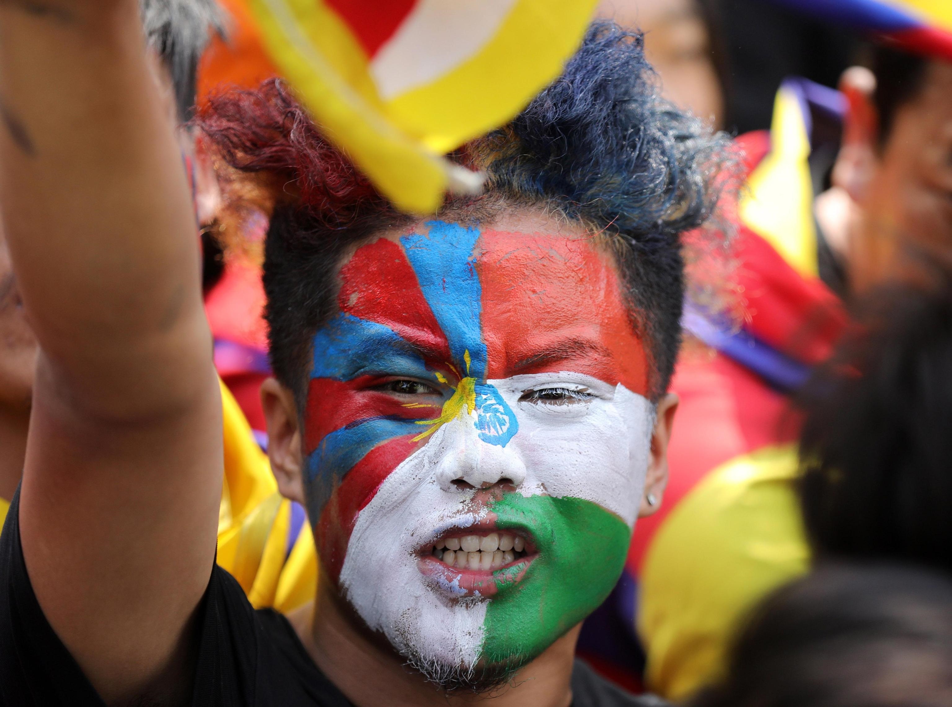 Un uomo con la bandiera tibetana pitturata sul volto
