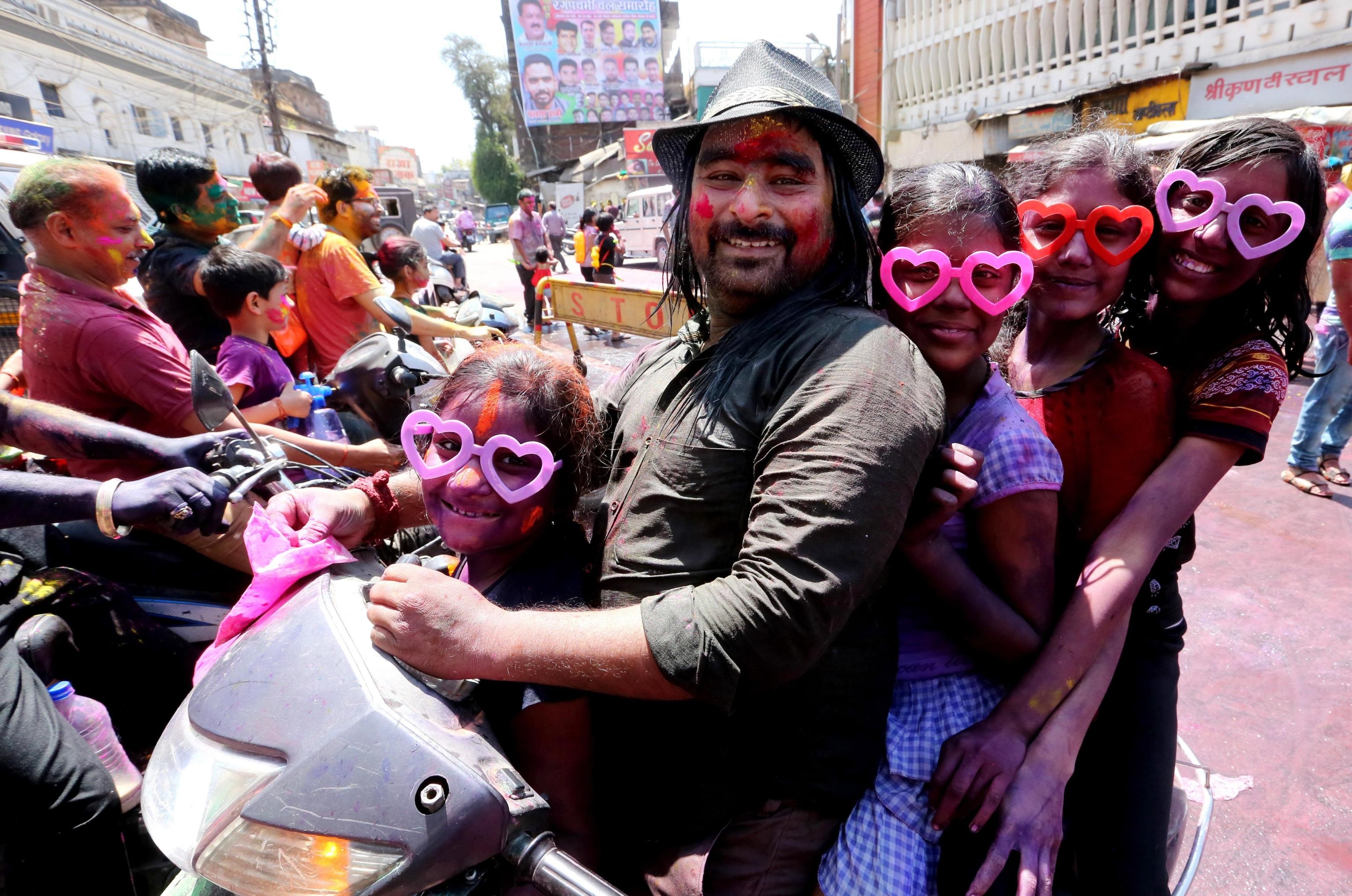 In cinque, tutti colorati, su uno scooter a Bhopal per l'Holi