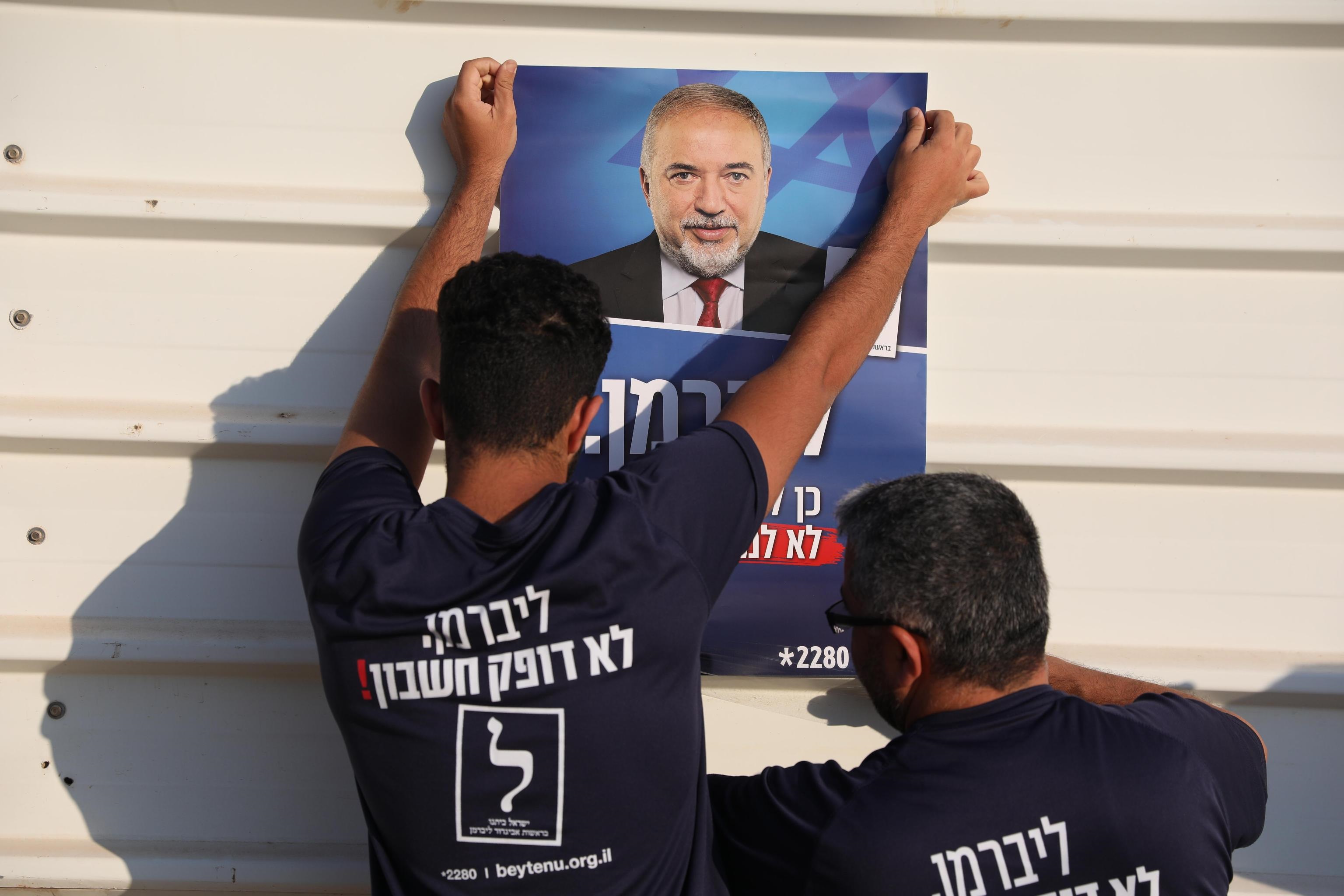 Attivisti appendono un poster del leader del partito politico Yisrael Beitenu