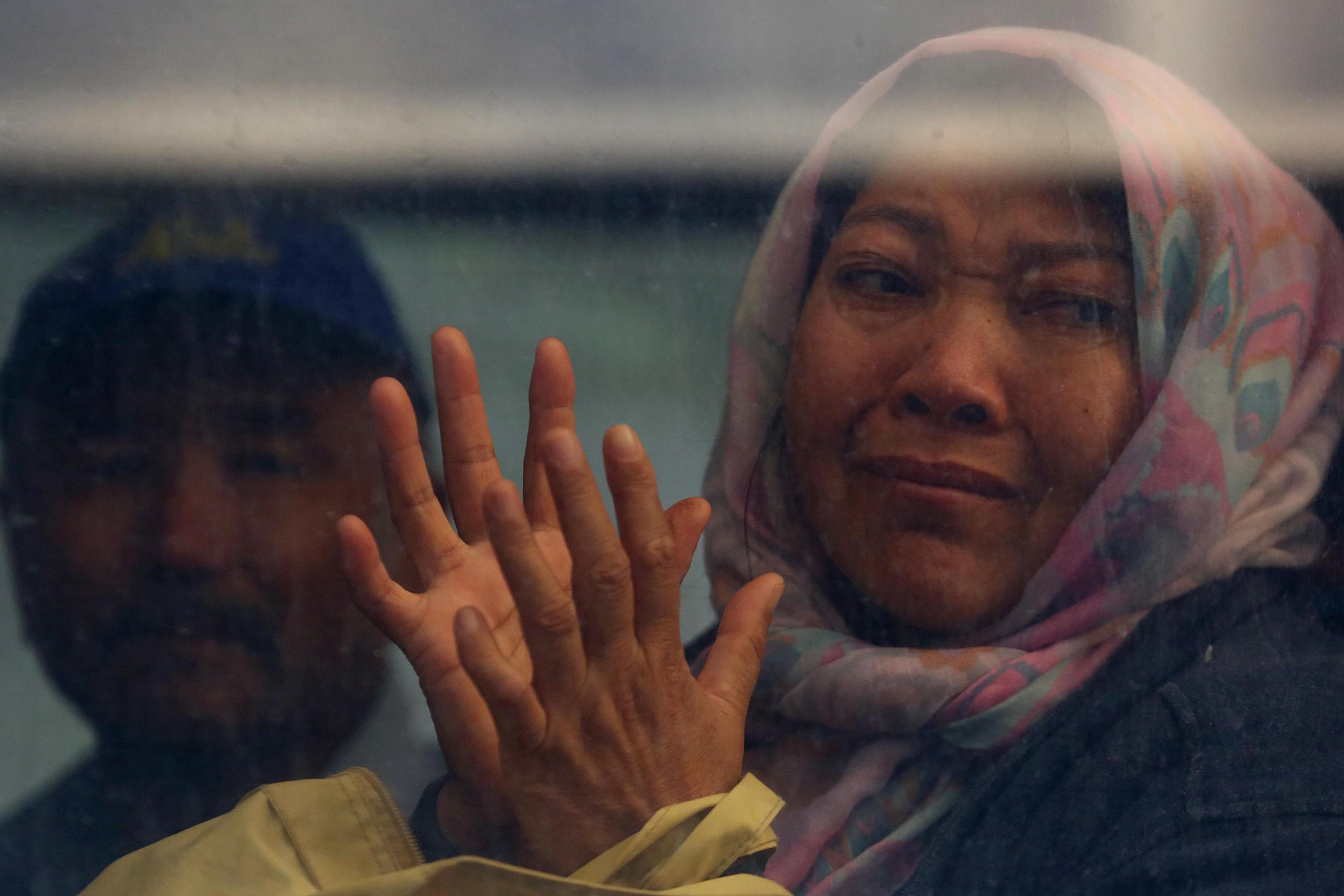 Una rifugiata guarda lo sgombero attraverso il vetro